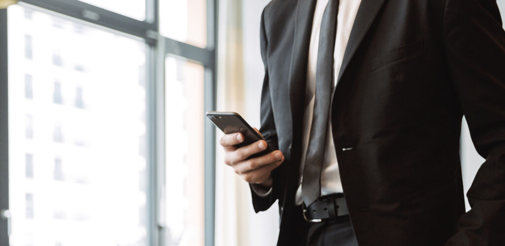A man in a suit checks his phone.