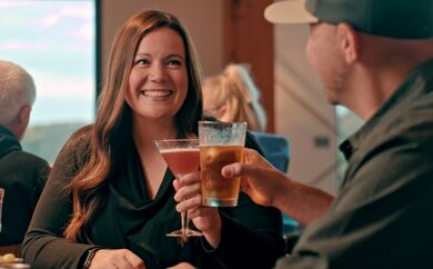 Woman holding drink in the air, looking at man