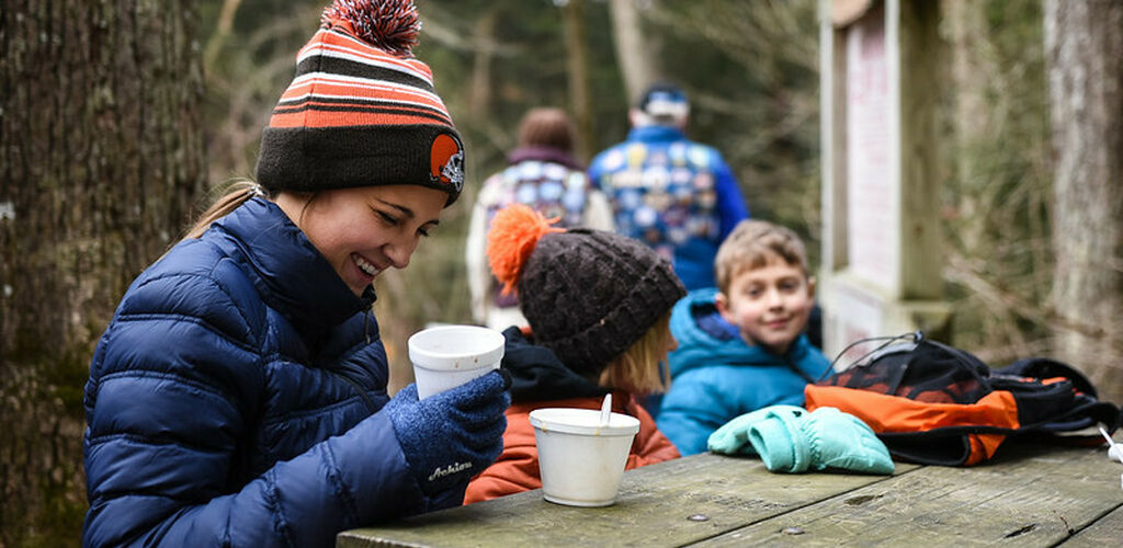 Woman enjoying a hot beverage at picnic table with child